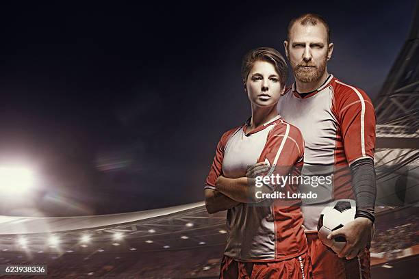 male and female football teammates posing in front of stadium - two guys playing soccer stockfoto's en -beelden