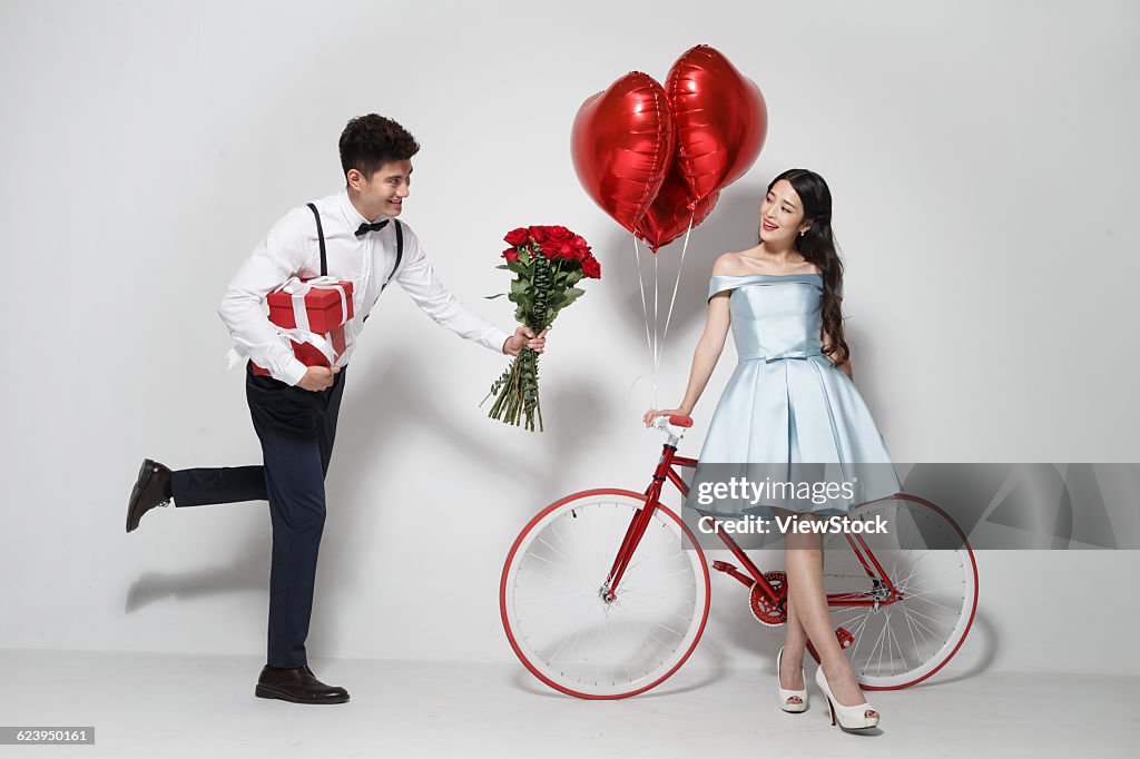 Young couple with heart-shaped balloons and gift