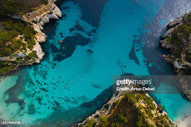 aerial picture taking with drone flying over the beautiful menorca island in the cala macarella beach with nice turquoise water and stunning landscape. - cala macarelleta - fotografias e filmes do acervo