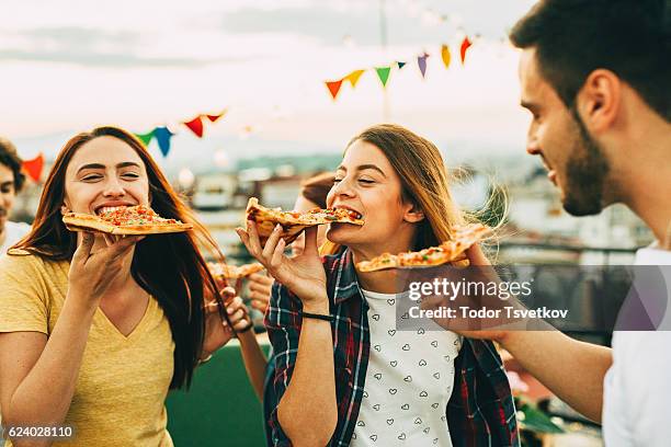 comer pizza en una fiesta en el techo - pizza fotografías e imágenes de stock