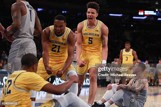 Zak Irvin and D.J. Wilson of the Michigan Wolverines celebrate with Muhammad-Ali Abdur-Rahkman after a foul against the Marquette Golden Eagles in...