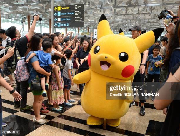 Fans gather to watch the Pokemon Go virtual reality game mascot Pikachu parade during a promotional event at the Changi International airport...