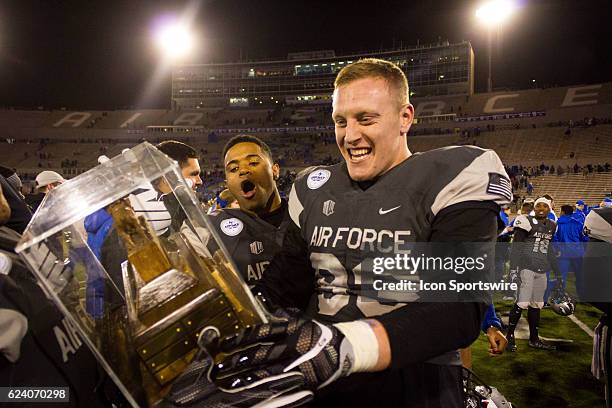 Air Force Falcons defensive lineman Samuel Byers gazes at the Ram-Falcon trophy as Air Force Falcons defensive lineman Ryan Darby looks in awe after...