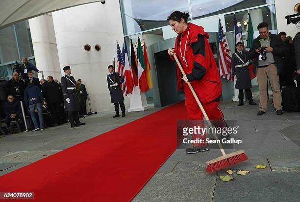 Facilities worker sweeps leaves from the red carpet prior to the arrival of U.S. President Barack Obama and western European leaders at the...