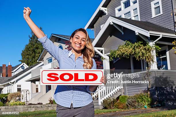 atractivo joven agente de bienes raíces hispano con signo vendido - ventas fotografías e imágenes de stock