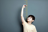 Cute boy is showing height on a wall scale
