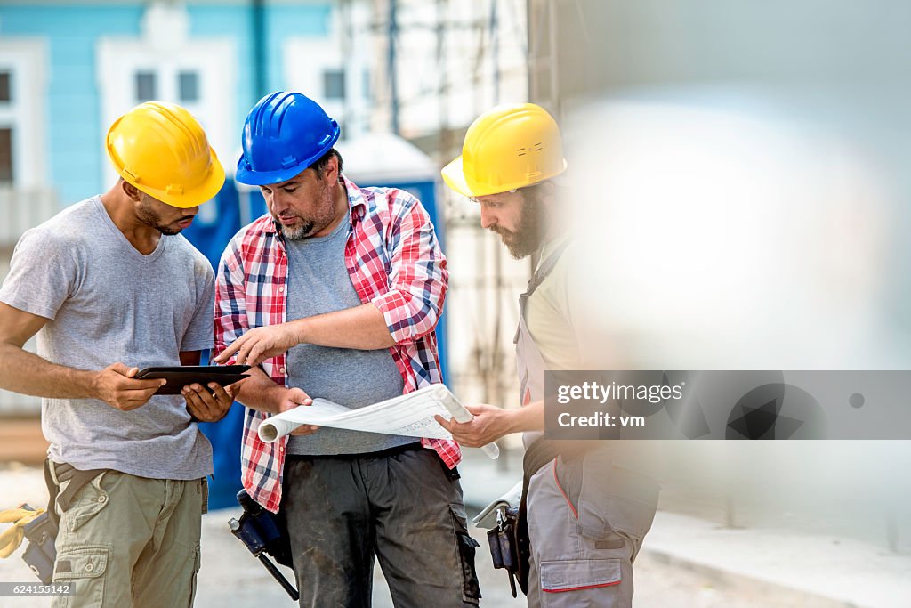 Three construction workers preparing for work