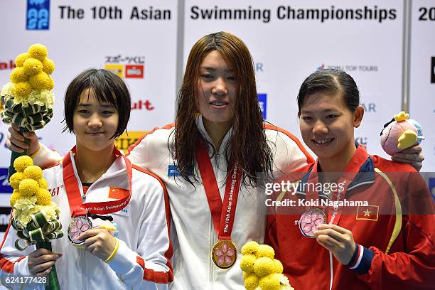 Silver medalist Ai Yanhan of China and Gold medalist Shen Duo of China and Nguyen Thi Anh Vien of Vietnam pose for photographs on the podium after...