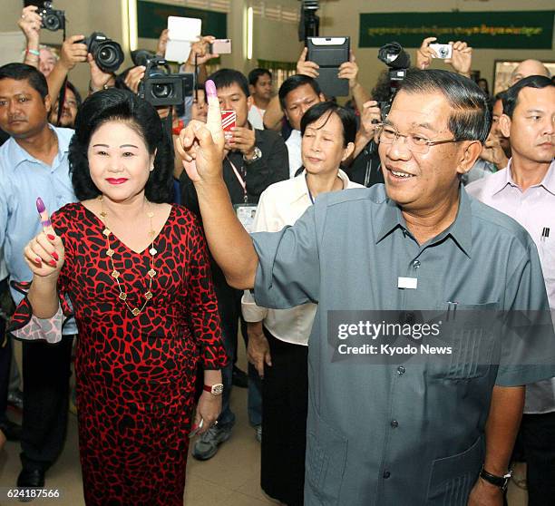 Cambodia - Cambodian Prime Minister Hun Sen and his wife Bun Rany show their ink-stained fingers after voting in the country's general election in...