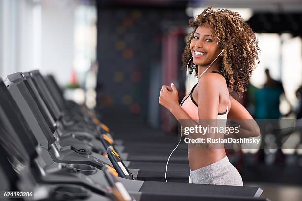 curled hair woman training at fitness club. - running on treadmill stock pictures, royalty-free photos & images