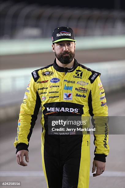 Paul Menard, driver of the Richmond/Menards Chevrolet, walks on the grid during qualifying for the NASCAR Sprint Cup Series Ford EcoBoost 400 at...