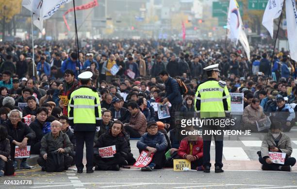 South Korean protesters sit on the street during an anti-government rally in central Seoul on November 19, 2016. Tens of thousands of protestors...