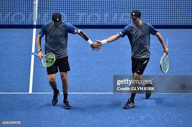 Player Bob Bryan and US player Mike Bryan touch hands between points against Finland's Henri Kontinen and his partner Australia's John Peers during...