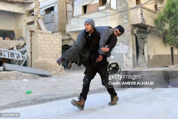 Syrian civil defence volunteer, known as the White Helmets, carries an injured man on November 19, 2016 following a reported air strike on Aleppo's...