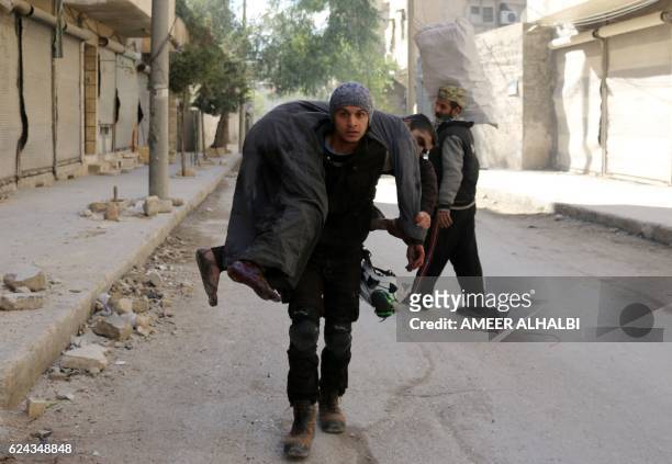 Syrian civil defence volunteer, known as the White Helmets, carries an injured man on November 19, 2016 following a reported air strike on Aleppo's...