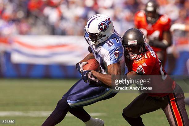 Kevin Dyson of the Tennessee Titans is pressured by Donnie Abraham of the Tampa Bay Buccaneers during the game at Adelphia Coliseum in Nashville,...