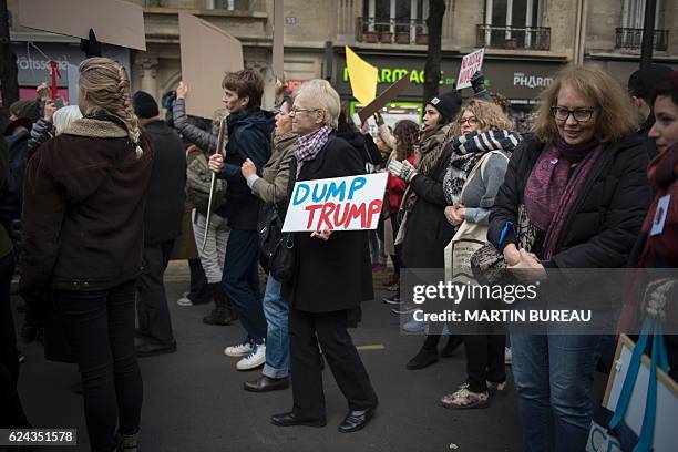 Woman holds a sign during a demonstration against US President-elect Donald Trump in Paris on November 19, 2016. / AFP / MARTIN BUREAU