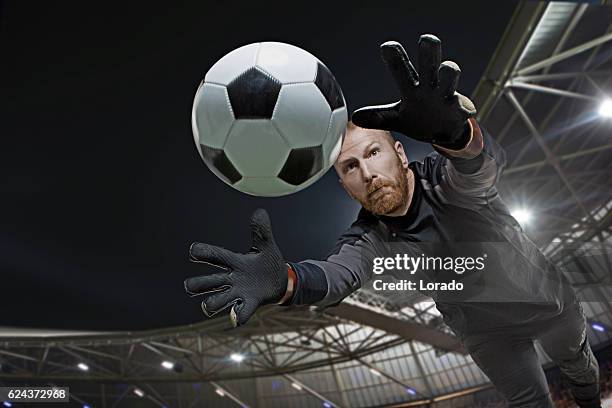 caucasian redhead adult male soccer player goalkeeper saving football - goalkeeper stock pictures, royalty-free photos & images