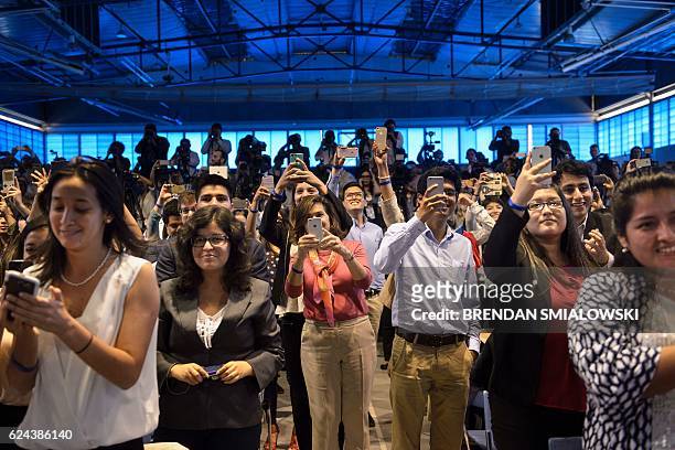 People take photos of US President Barack Obama during a Young Leaders of the Americas Initiative town hall meeting at the Pontifical Catholic...