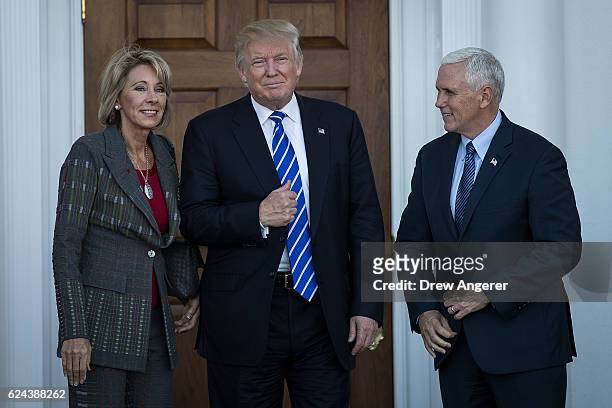 Betsy DeVos, president-elect Donald Trump and vice president-elect Mike Pence pose for a photo outside the clubhouse at Trump International Golf...