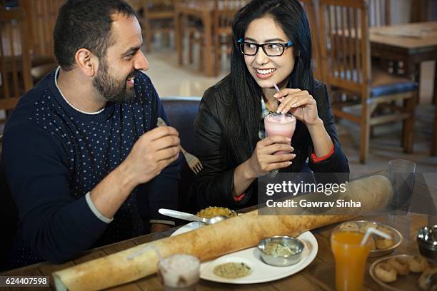casal jovem multiétnico comendo comida do sul da índia em restaurante. - indian food - fotografias e filmes do acervo