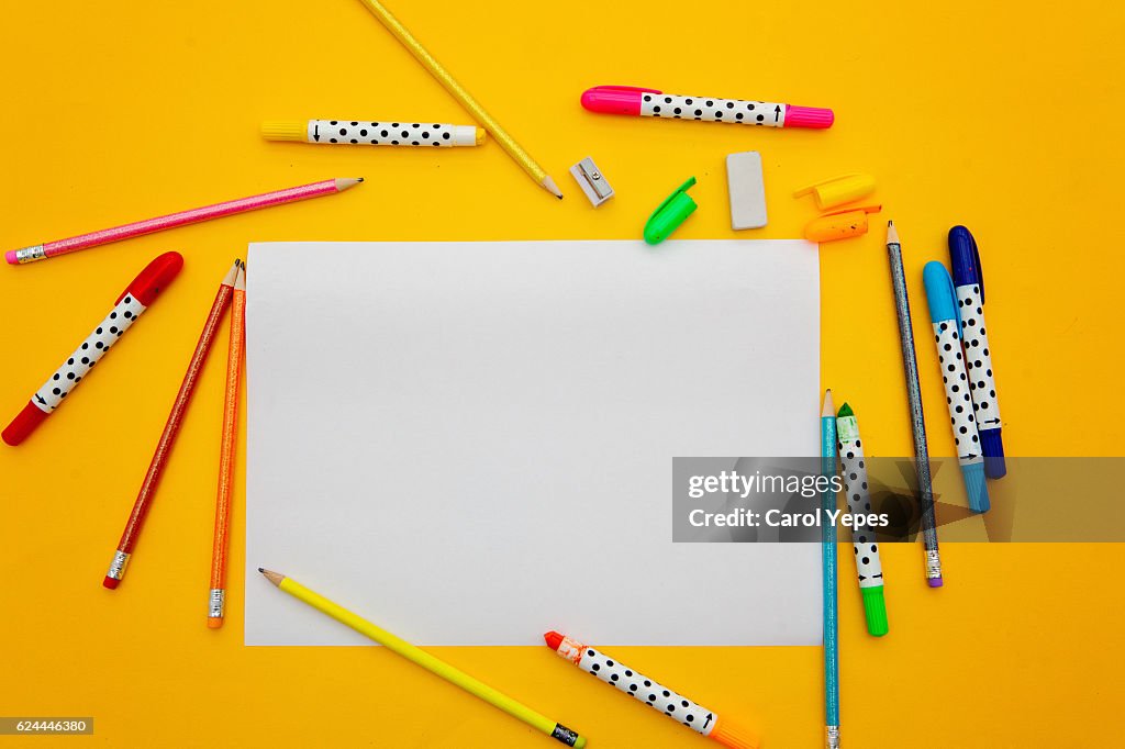 Paper and color pens in a yellow background