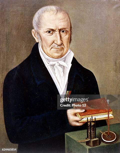 Alessandro Volta, Italian physicist. On table are two of his inventions, the Voltaic pile on left,_and electrophorus, an apparatus demonstrating...