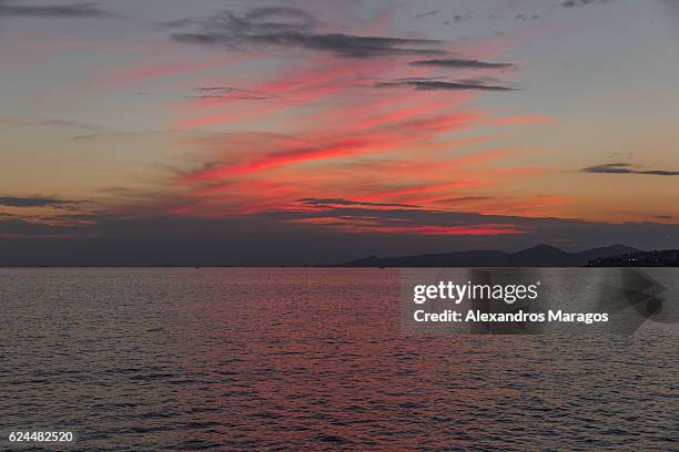 sunset with red cloud formations over sea - alexandros maragos stock pictures, royalty-free photos & images