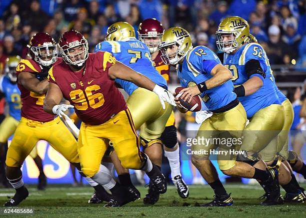Quarterback Mike Fafaul of the UCLA Bruins scrambles out of the pocket as he is chased by defensive tackle Stevie Tu'ikolovatu of the USC Trojans...