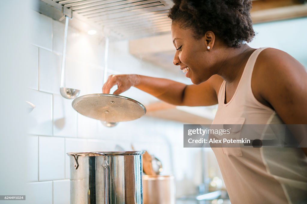 Joven mujer negra bonita hacer sopa en la cocina