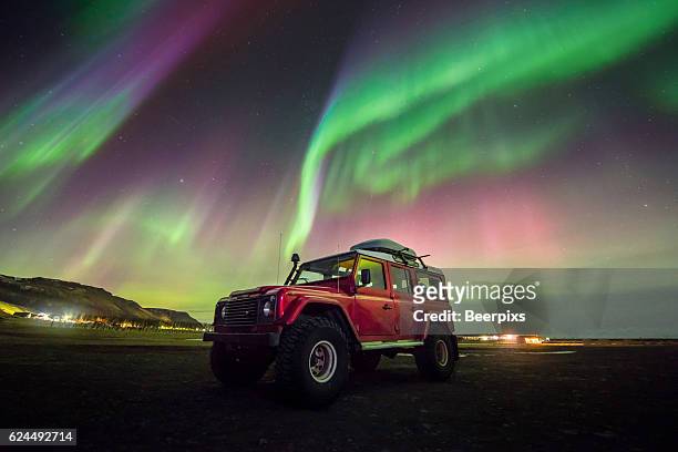 beautiful aurora dancing over a red car. - aurora australis stock pictures, royalty-free photos & images