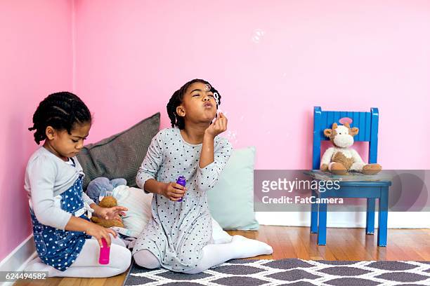 jeune fille afro-américaine soufflant des bulles pour le plaisir - fat twins photos et images de collection
