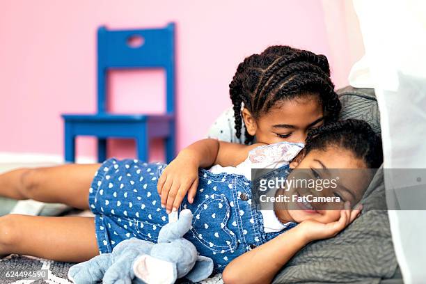 nette afroamerikanische mädchen entspannen zusammen auf dem boden - fat twins stock-fotos und bilder