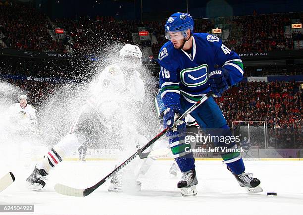 Nick Schmaltz of the Chicago Blackhawks checks Jayson Megna of the Vancouver Canucks during their NHL game at Rogers Arena November 19, 2016 in...