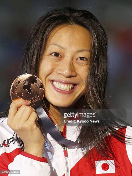 Spain - Japan's Aya Terakawa at the award ceremony shows the bronze medal she won in the women's 50-meter backstroke at the world swimming...