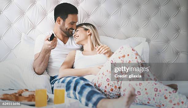 pareja viendo la televisión en el dormitorio. - motel pareja fotografías e imágenes de stock