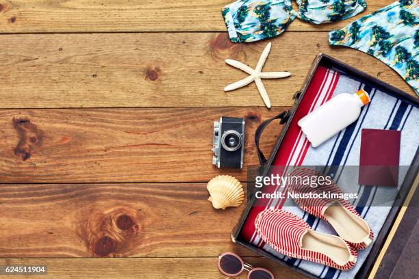 offener koffer mit sommerferienausrüstung flach auf holz gelegt - summer travel bag stock-fotos und bilder