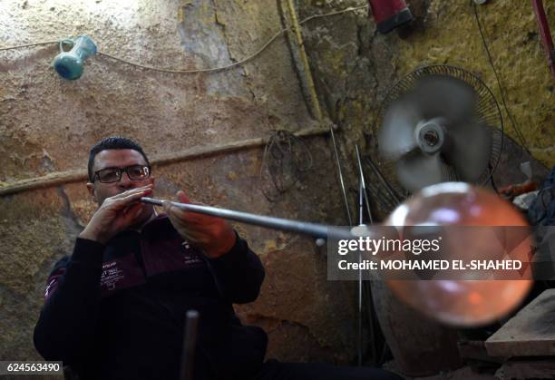 Kamal the son of Ahmed Ali, also known as Hassan Hodhod, one of Egypt's few remaining glassblowers and former boxer, blows glass inside his father's...