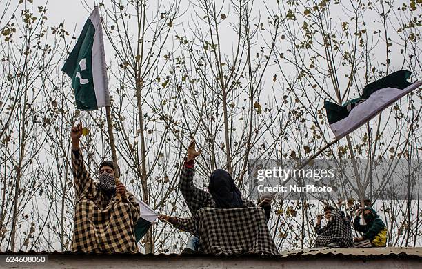 Kashmiri Muslims hold flags on roof tops as they shout anti Indian and Pro Kashmir freedom slogans while attending the funeral of Rayees Ahmad, a...