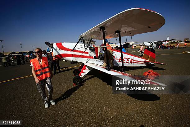 Officials walk past the vintage Bucker Bu 131 biplane as it sits on the runway on November 20, 2016 in Khartoum airport during the Vintage Air Rally...