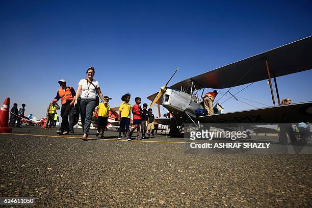 Children walk past the vintage de Havilland Tiger Moth biplane as it sits on the runway on November 20, 2016 in Khartoum airport during the Vintage...