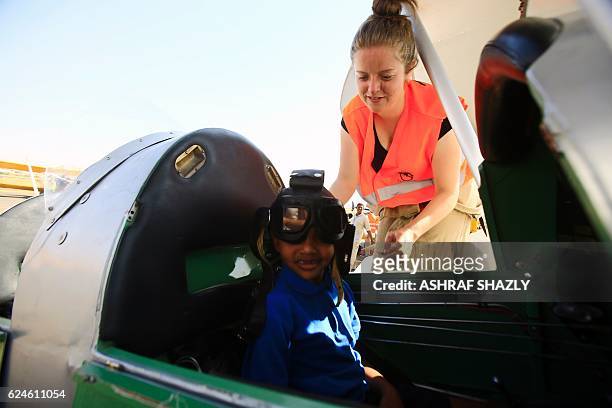 Child sits in the cockpit of the vintage de Havilland Tiger Moth biplane as it sits on the runway on November 20, 2016 in Khartoum airport during the...