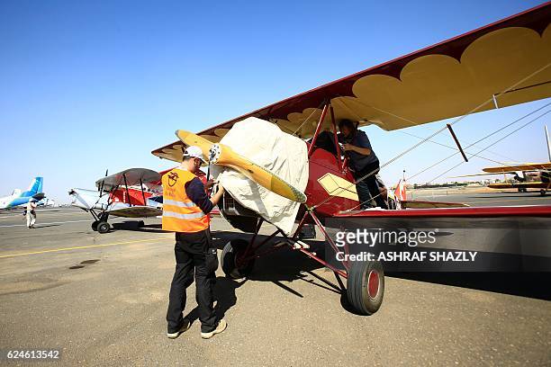 Officials cover the vintage Travel Air 2000 biplane as it sits on the runway on November 20, 2016 in Khartoum airport during the Vintage Air Rally ....