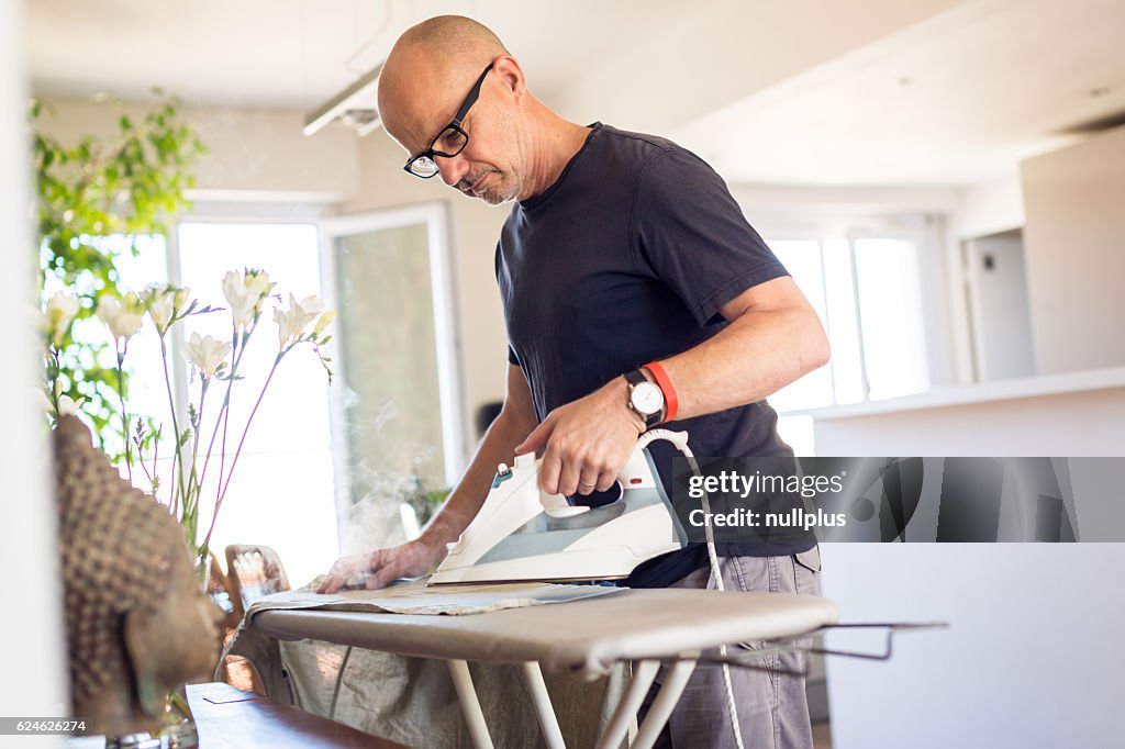 Adult man ironing his shirt at home