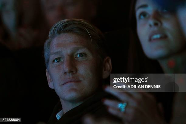 Serbia's Ana Ivanovic and Manchester United's German footballer Bastian Schweinsteiger sit in the crowd to watch Novak Djokovic returns play against...