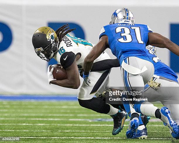 Denard Robinson of the Jacksonville Jaguars tries to avoid the tackle from Darius Slay and Rafael Bush of the Detroit Lions during an NFL game at...