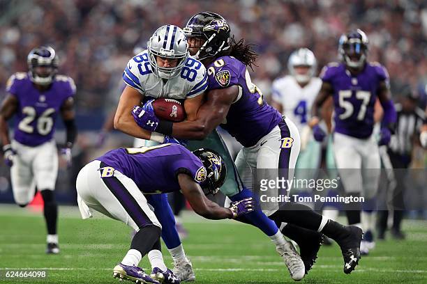 Gavin Escobar of the Dallas Cowboys is tackled by Shareece Wright and Za'Darius Smith of the Baltimore Ravens after catching a pass during the second...