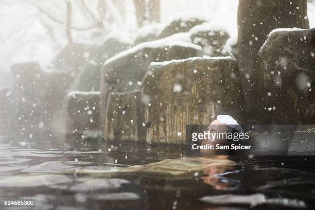western tourist enjoying natural hot spring onsen during winter snow - european spring foto e immagini stock
