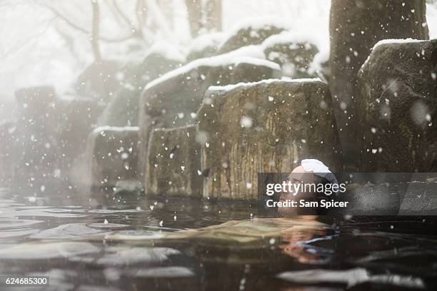 western tourist enjoying natural hot spring onsen during winter snow - fonte termal imagens e fotografias de stock