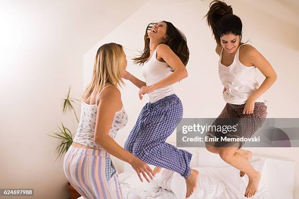 mulheres brincalhonas se divertindo em festa do pijama pulando na cama - roupa de dormir - fotografias e filmes do acervo